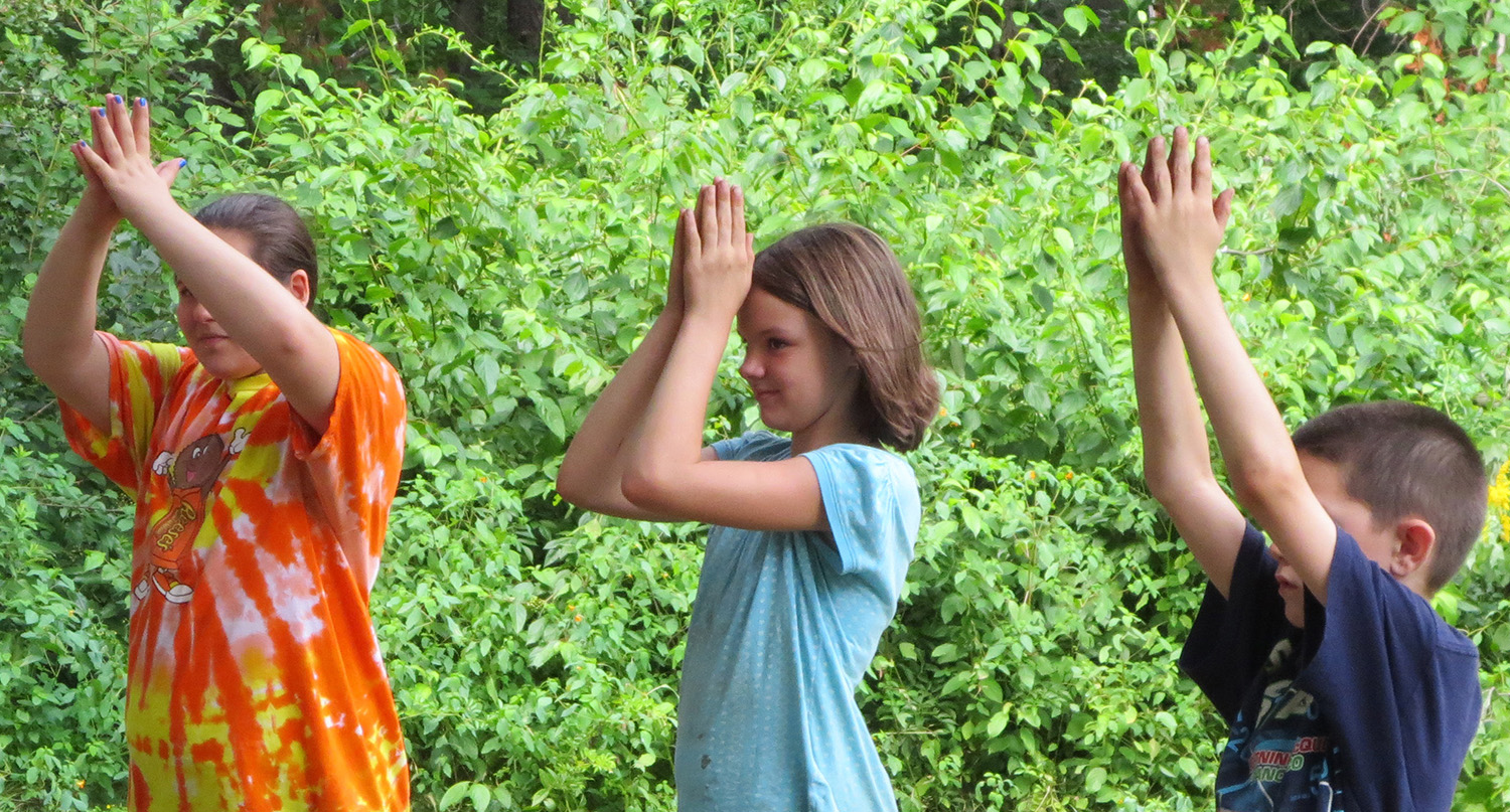 Three kids playing a hand gesture game outdoors.