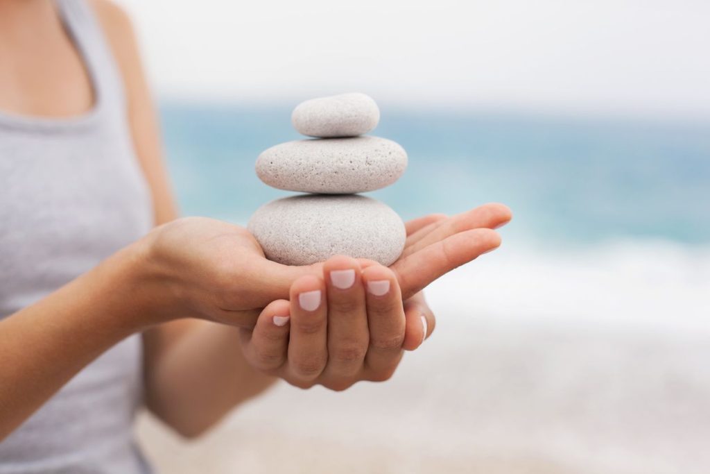 Stack of smooth stones balanced on a person's hand, symbolizing calm and balance.