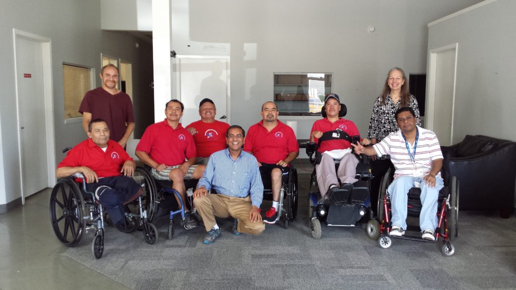 Group of people, some in wheelchairs, posing indoors.