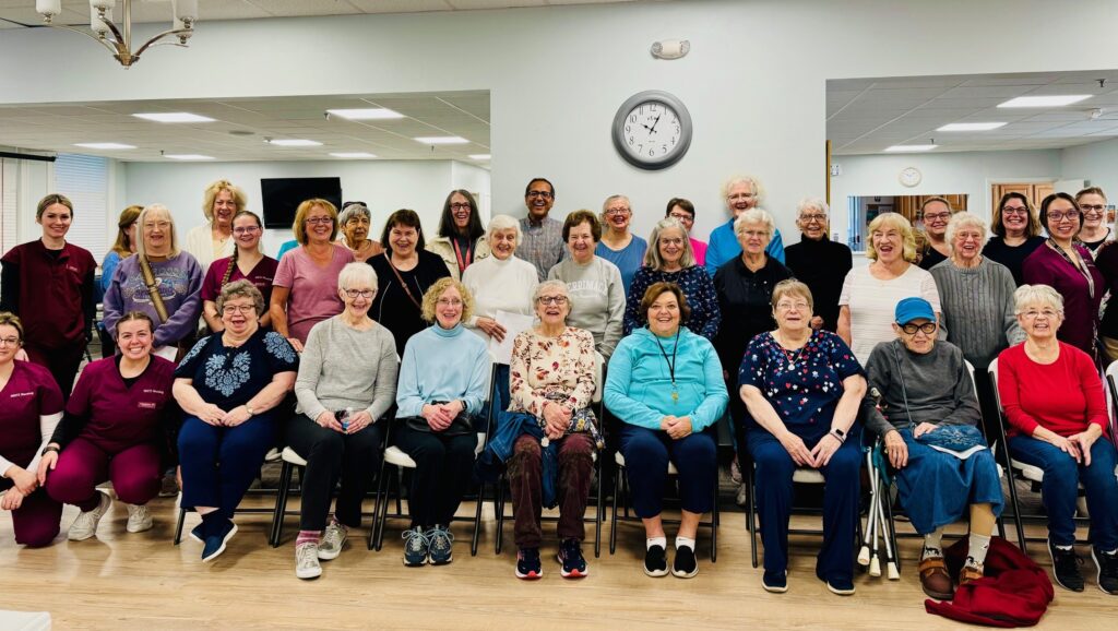 A group photo of elderly people gathered indoors, smiling.