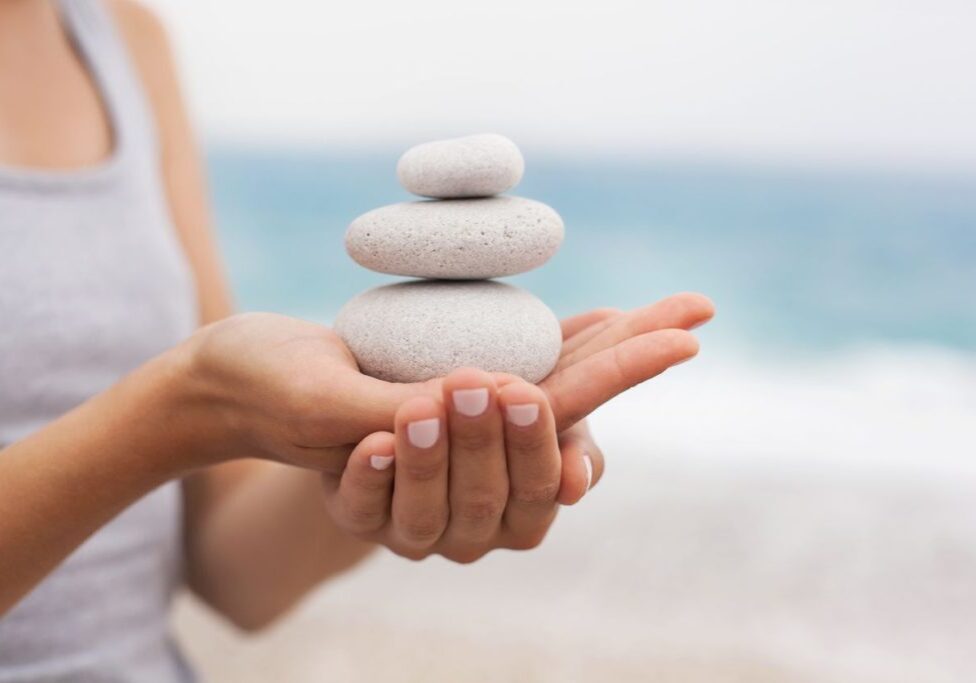 Stack of smooth stones balanced on a person's hand, symbolizing calm and balance.